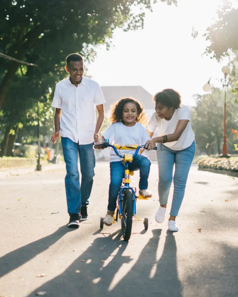 Man Standing Beside His Wife Teaching Their Child How to Ride Bicycle