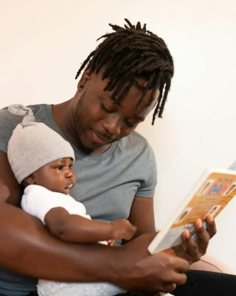 A Man Reading a Book to his Baby