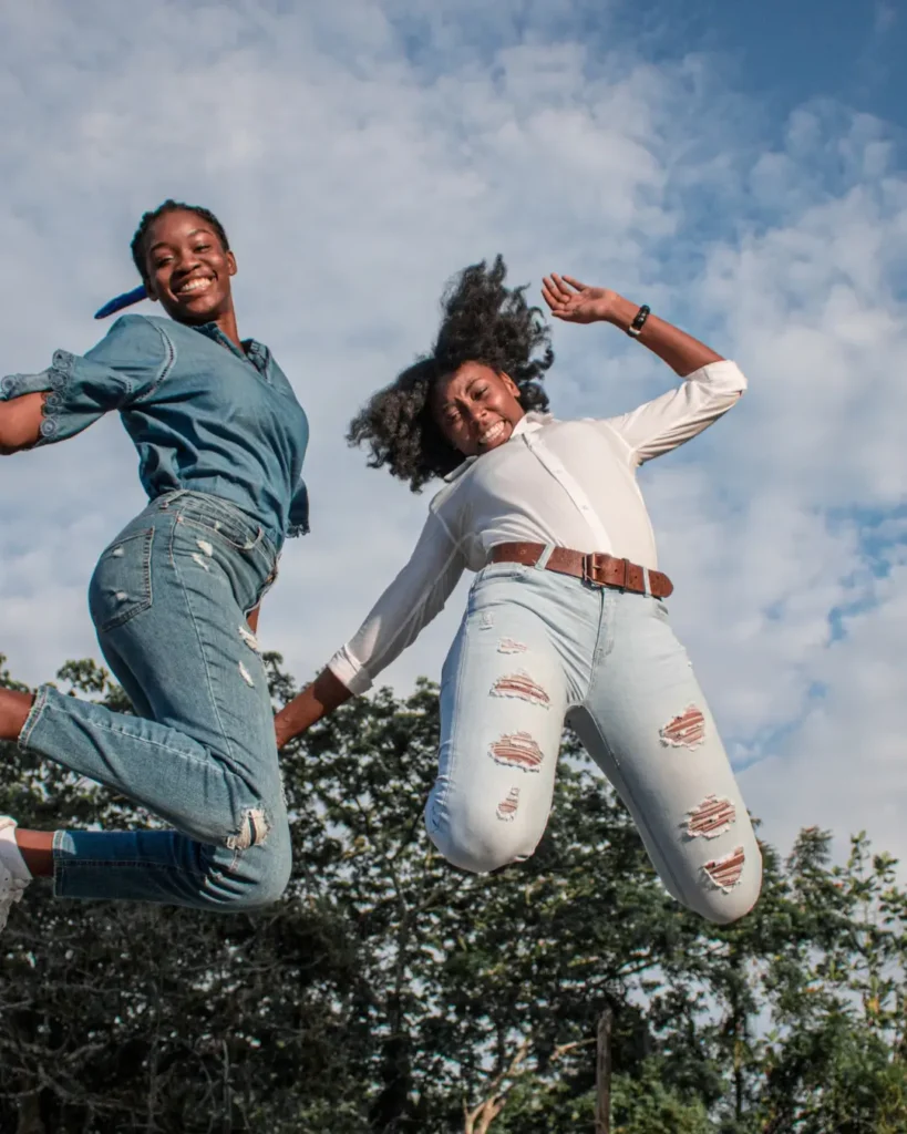 Energetic happy black women jumping in summer forest