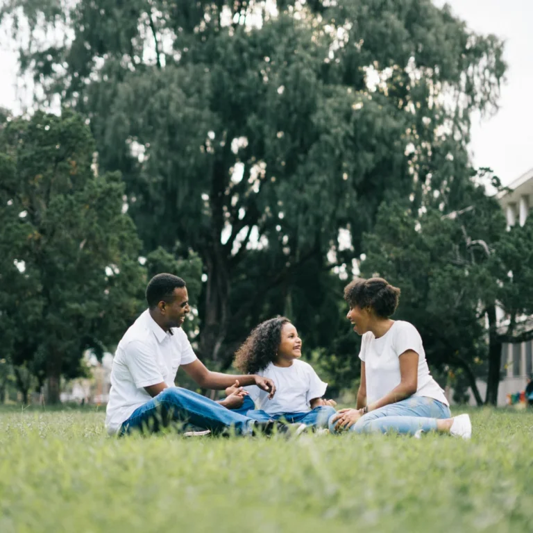 Family Sitting on Grass Near Building