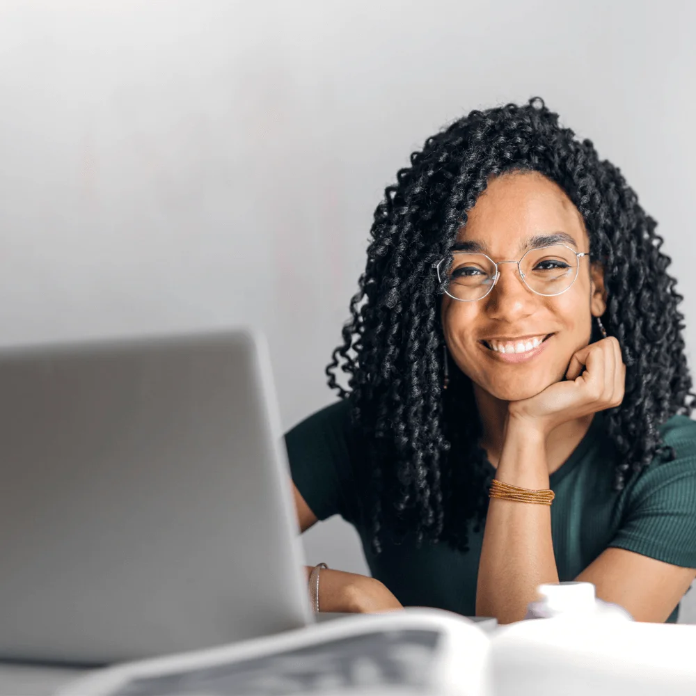 Happy ethnic woman sitting at a table with a laptop.