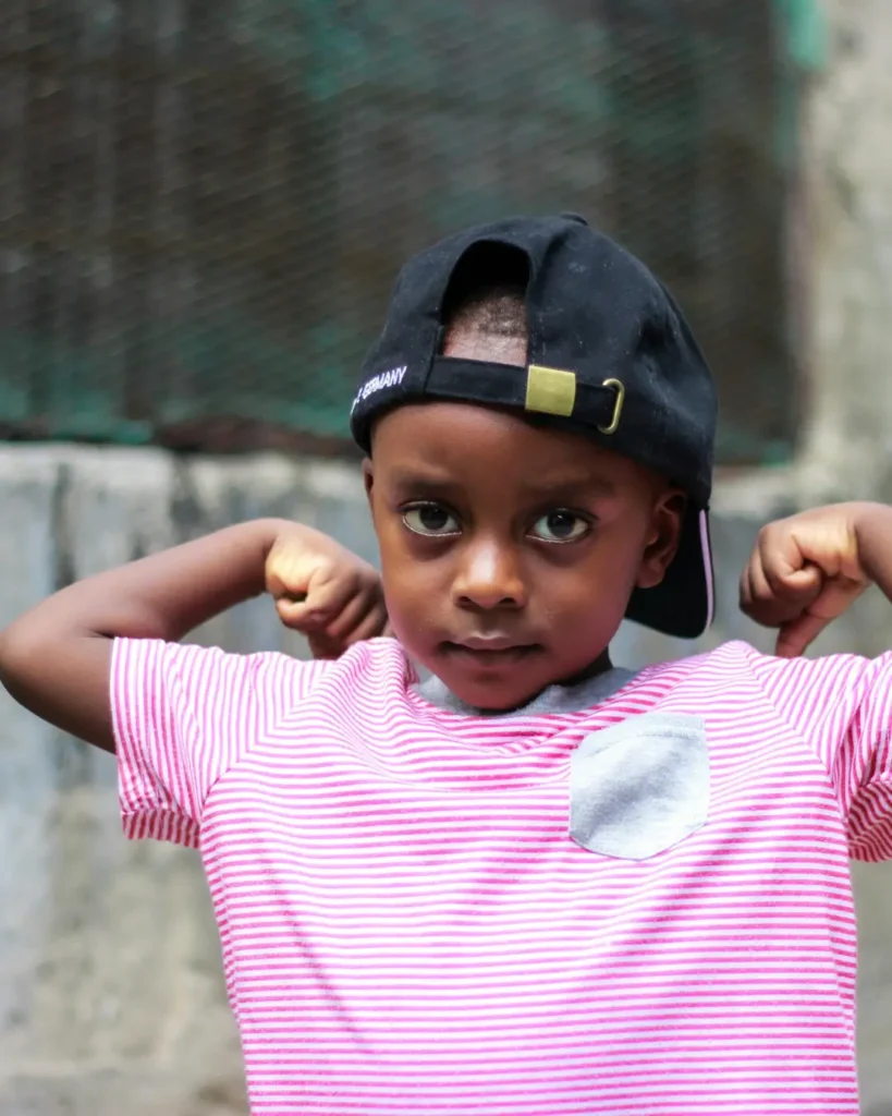 Confident Young Boy Flexing Muscles Outdoors
