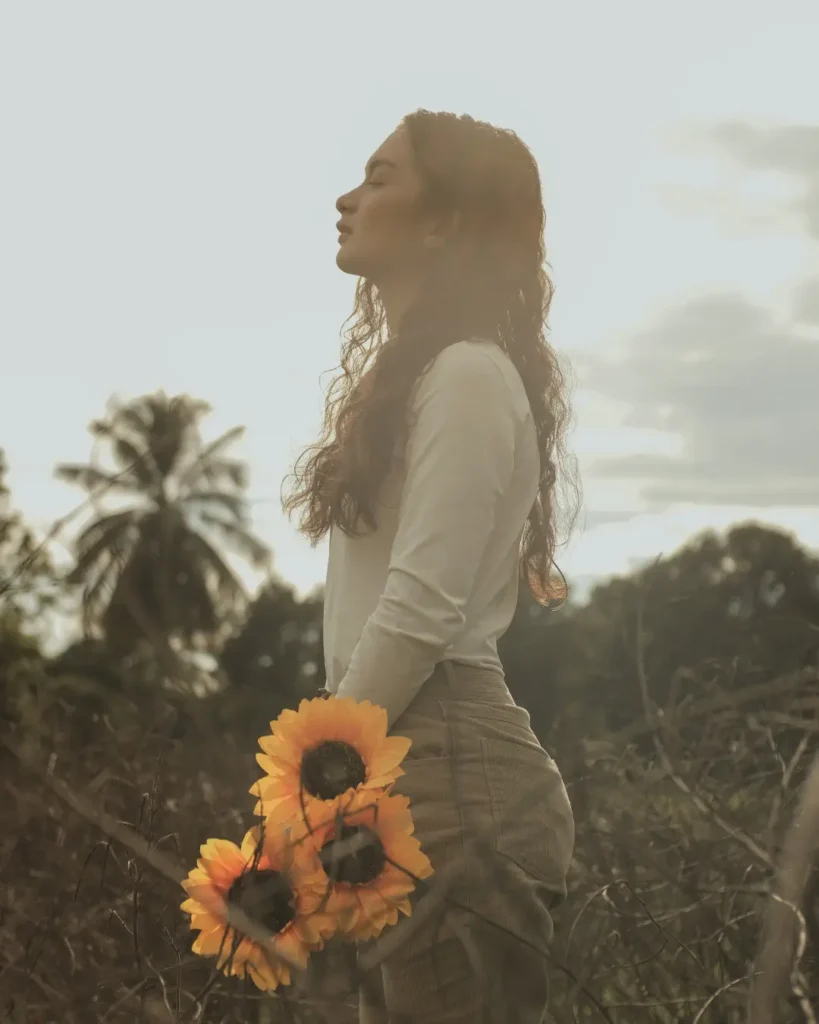 Side View of a Young Woman Holding Sunflowers