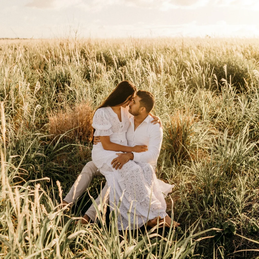 a couple dressed in white in a grassfield