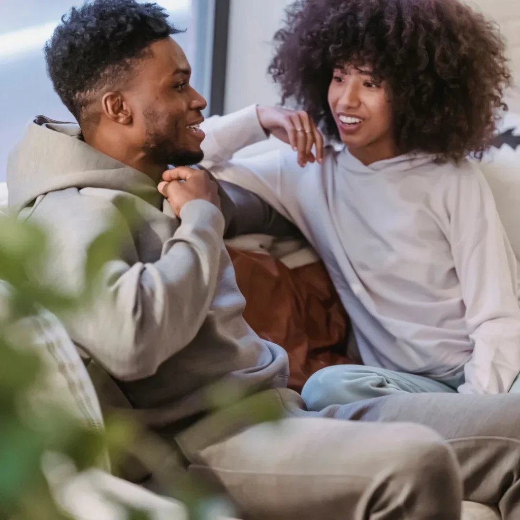 a couple smiling and talking on a sofa. Marital Scriptures