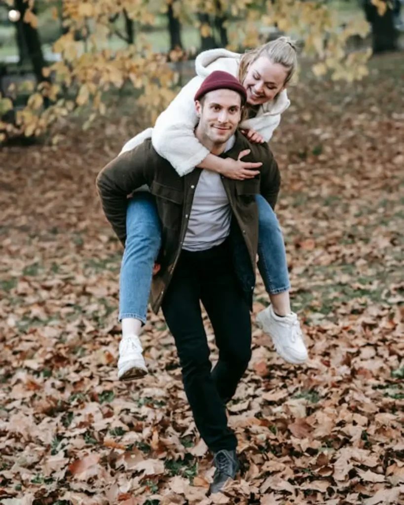 Romantic young male giving piggyback ride to happy girlfriend in nature