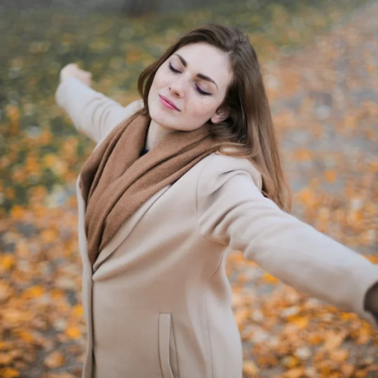 Woman in Beige Long Sleeve Coat Standing on Brown Leaves