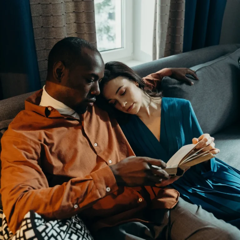 man and woman hugging and reading a book on a sofa