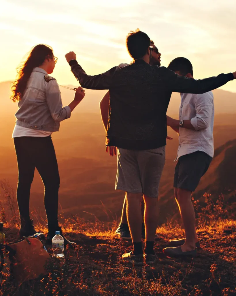 Four Person Standing at Top of Grassy Mountain