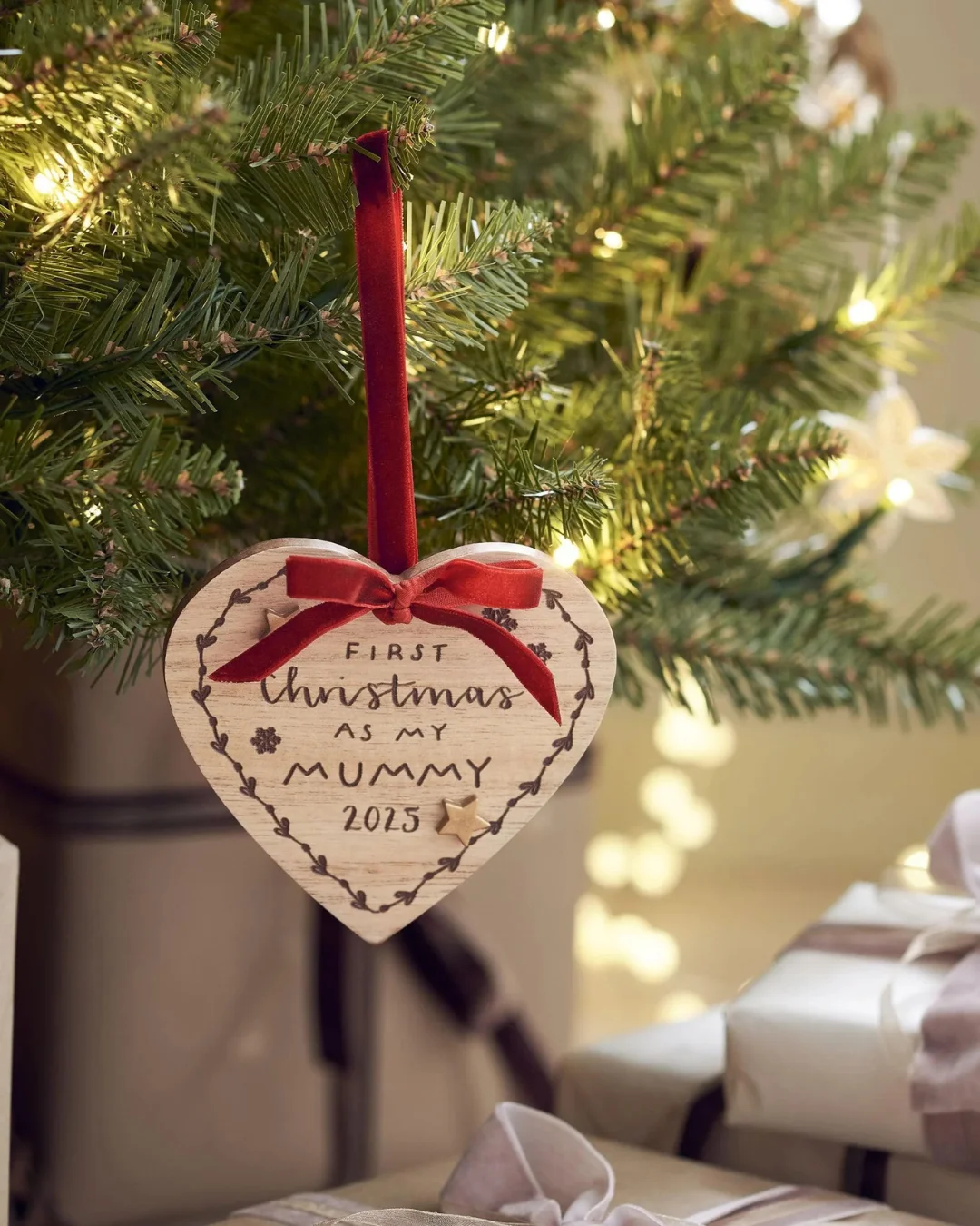 A love heart-shaped brown bauble with a red bow ribbon with a personalisation. 