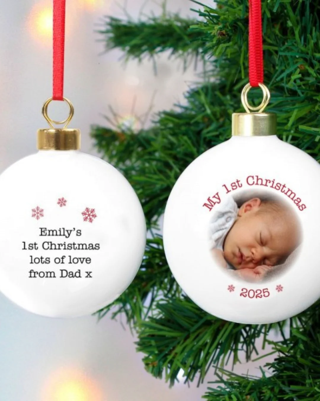 A white bauble hanging from a christmas tree, with a picture of a sleeping baby at the front and a personalisation message on the back. 