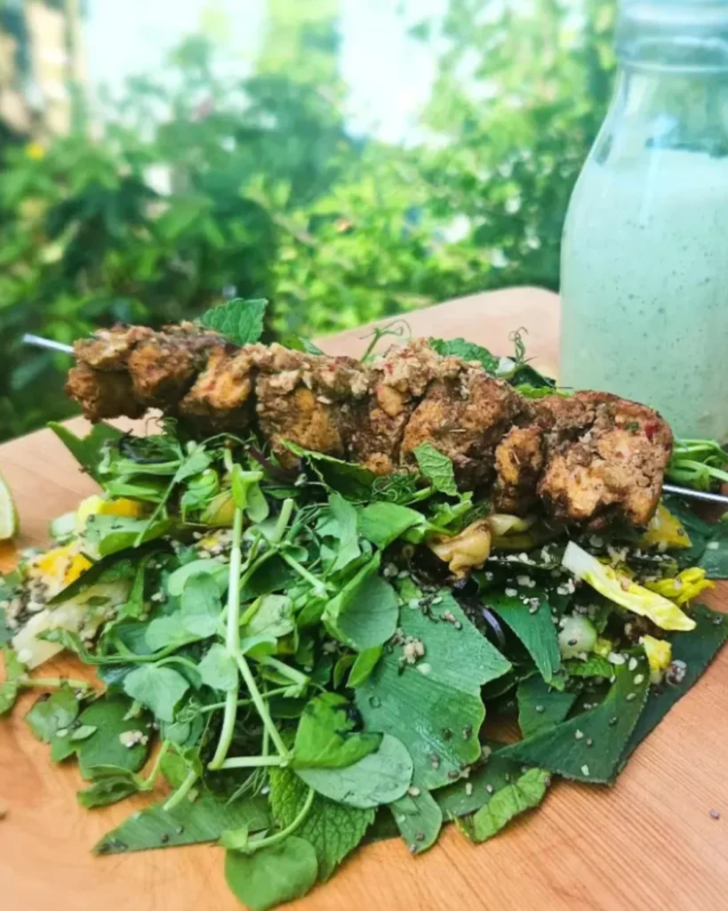On a bed of caesar salad, is a skewer of tofu jerk.