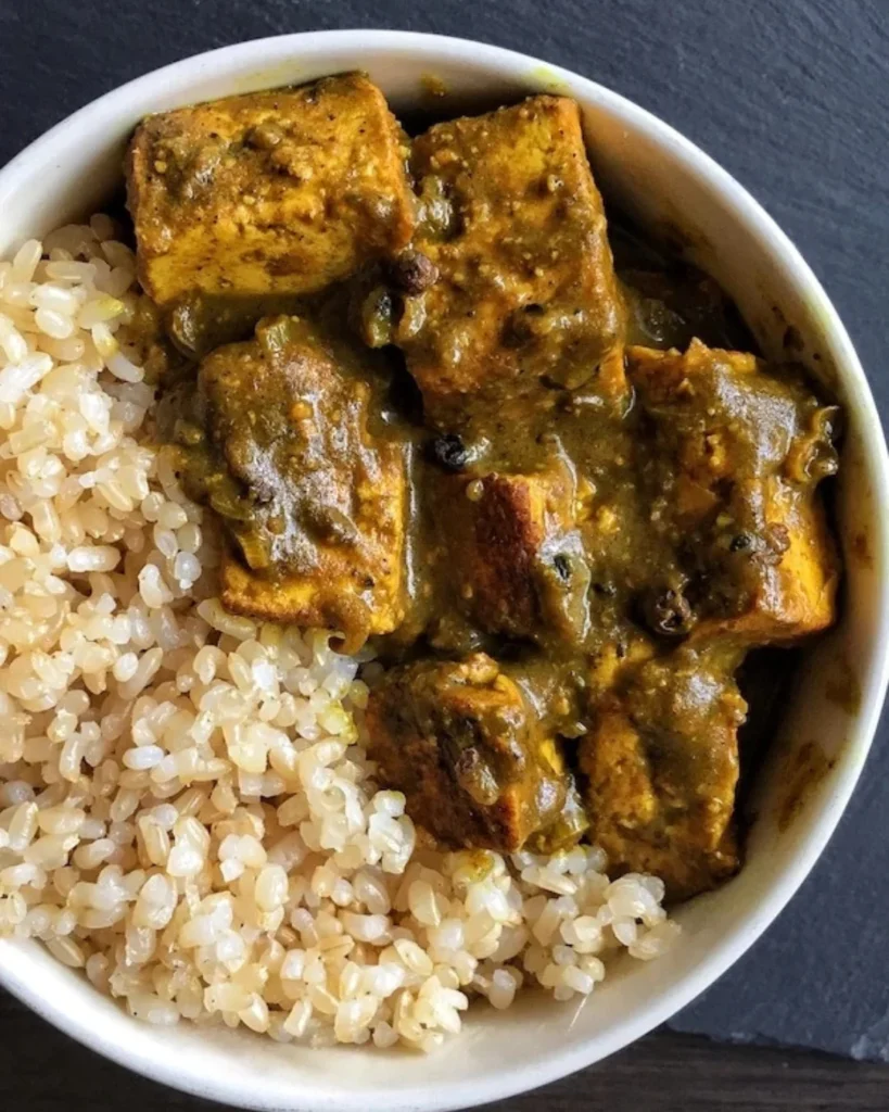 A white bowl filled with a creamy curry tofu and rice.