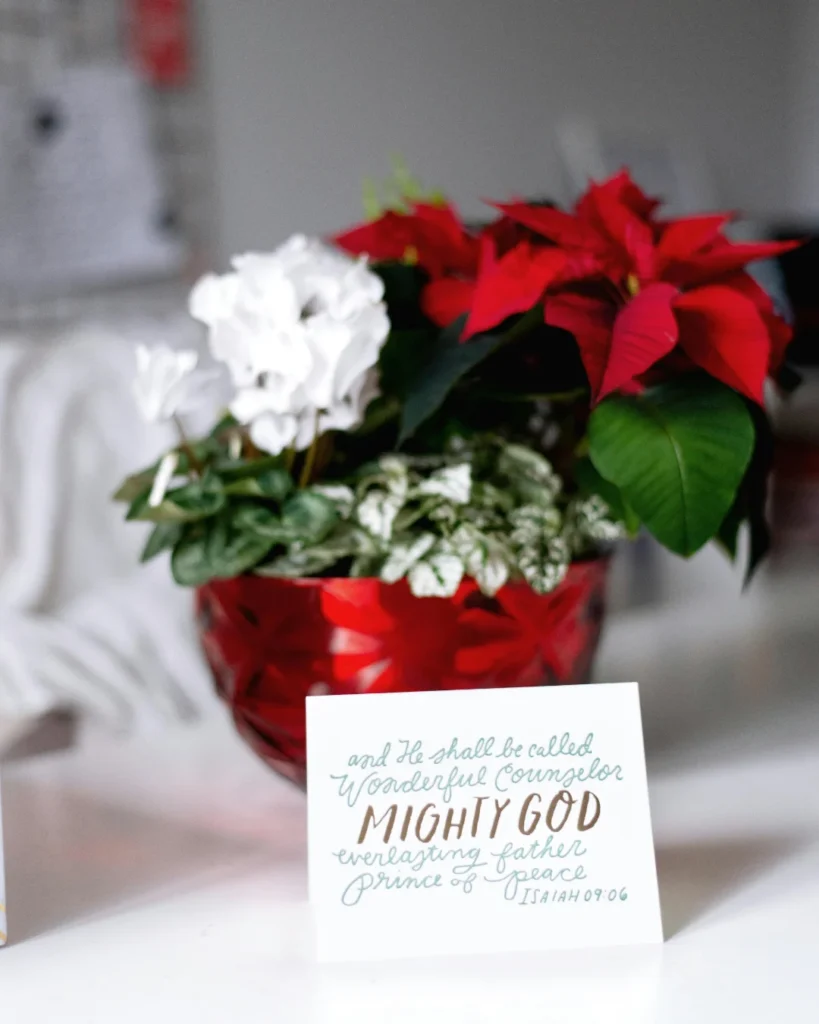 Christian Wishes on Card, leaning on a red bowl with white and red flowers.