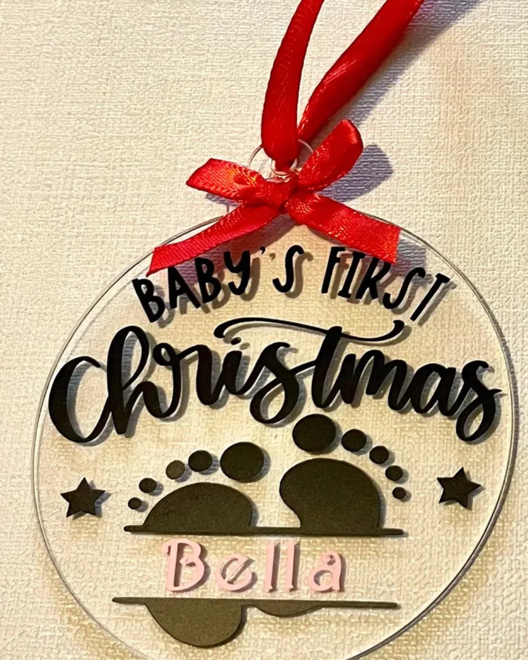 Flat hanging bauble with a red ribbon and baby footprints. 