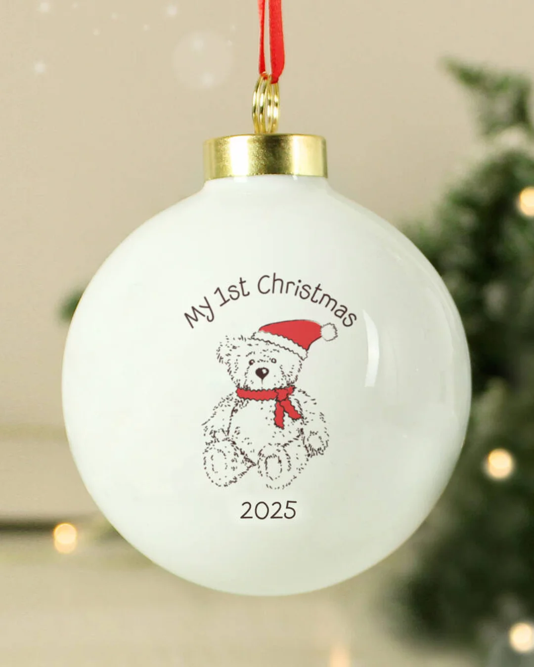 A teddy bear wearing a red hat and scarf, in a bauble.