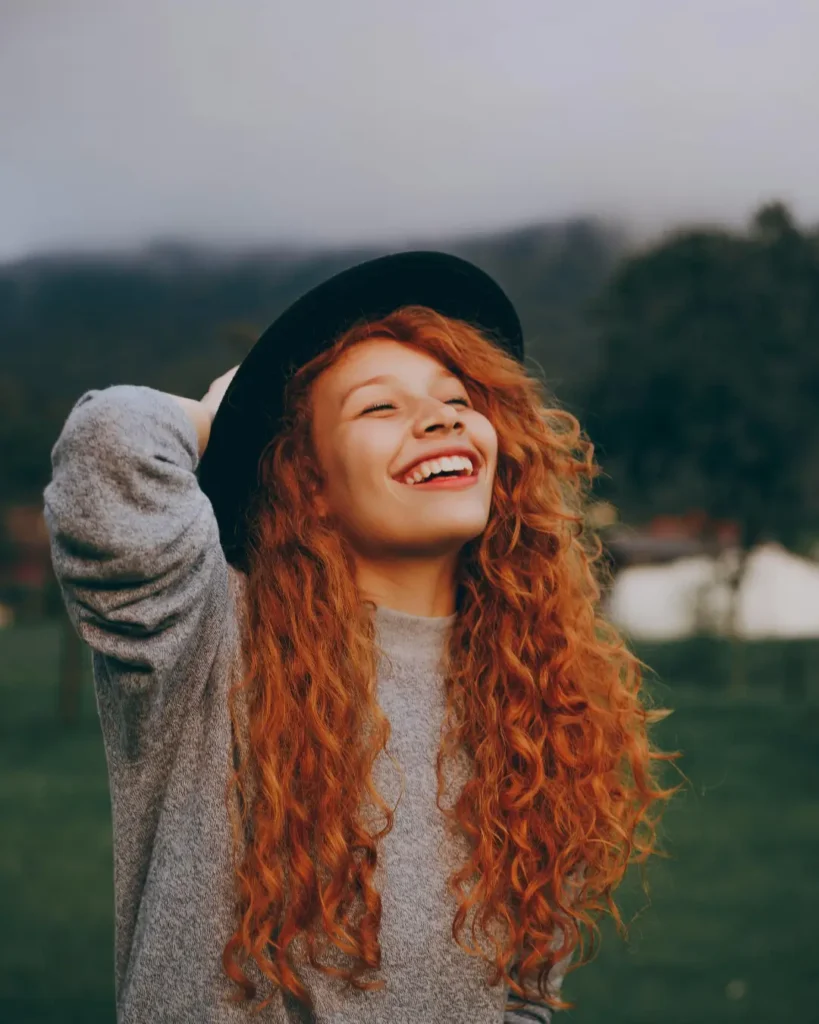 Woman Holding Her Hat While Smiling