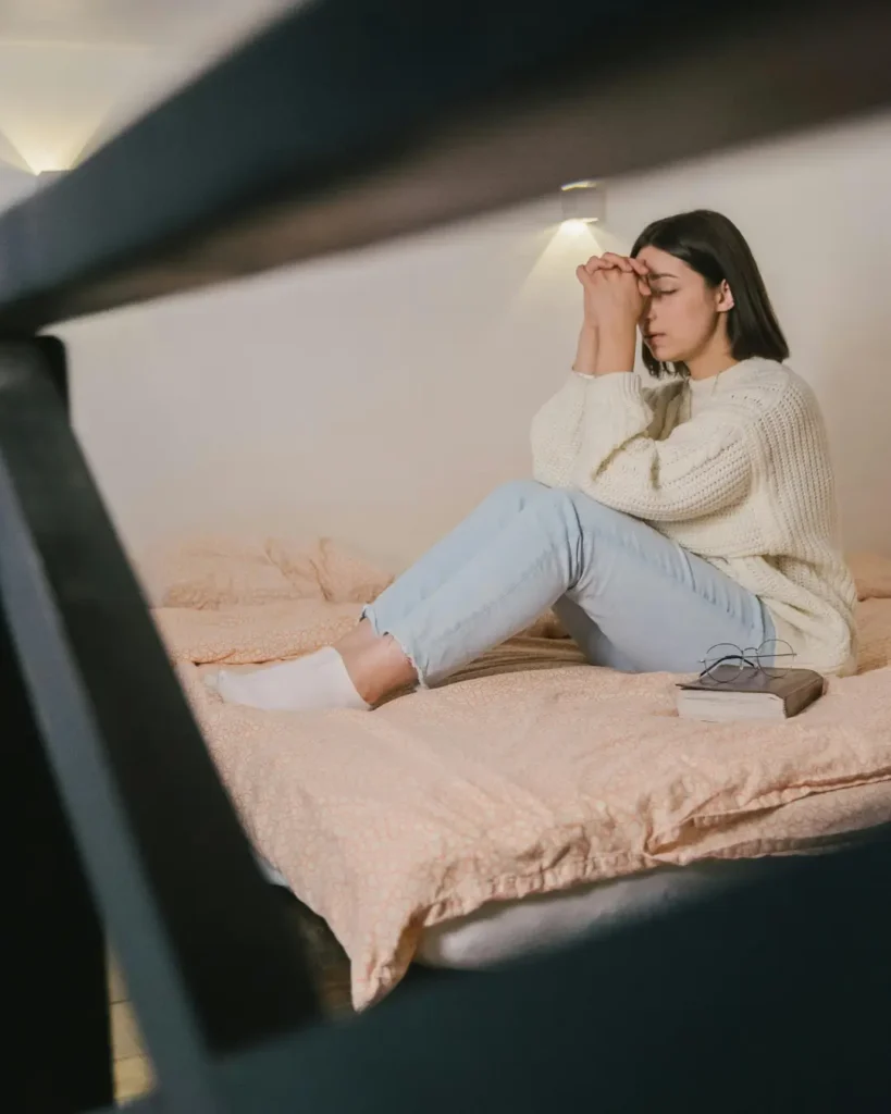 Woman in White Sweater and Blue Denim Jeans Sitting on Bed