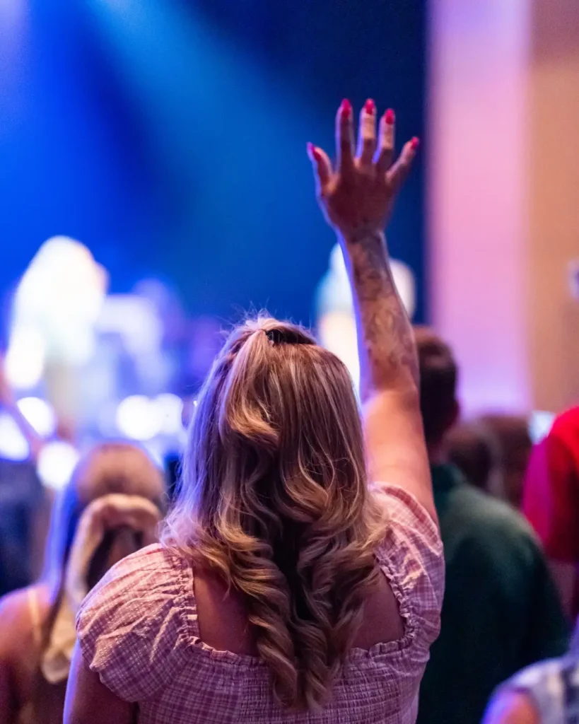 A Back View of a Woman Raising Her Hand while Worshipping