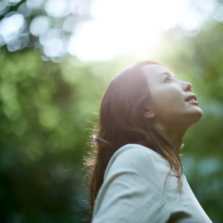 Woman Gazing at Sunlight in a Forest