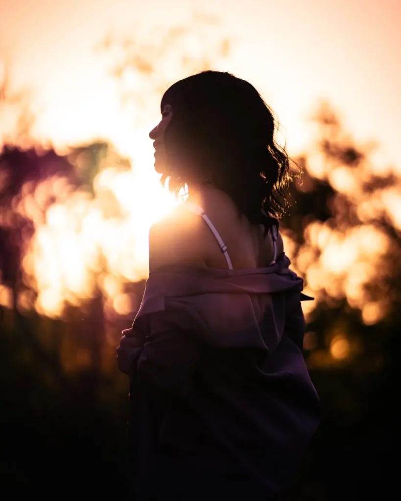 A Woman Standing Outdoors at Sunset