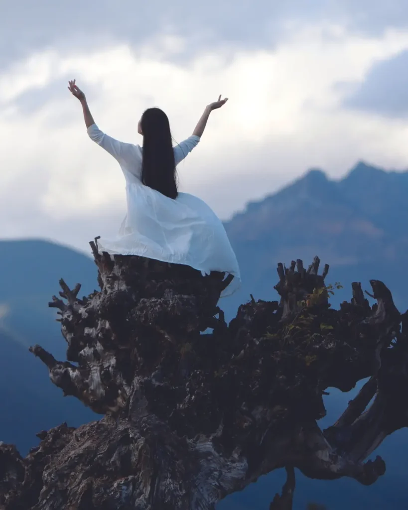 A Woman in White Dress Standing on Tree Trunk