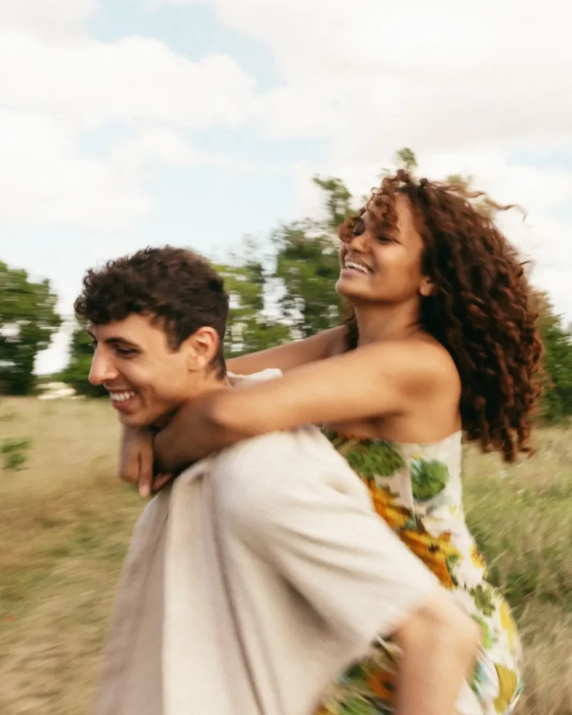Woman Rides Piggyback on Man in Field