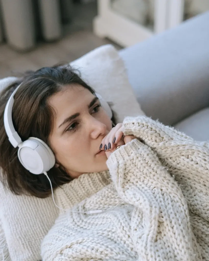 A Woman Lying Down in a Couch Wearing Headphones