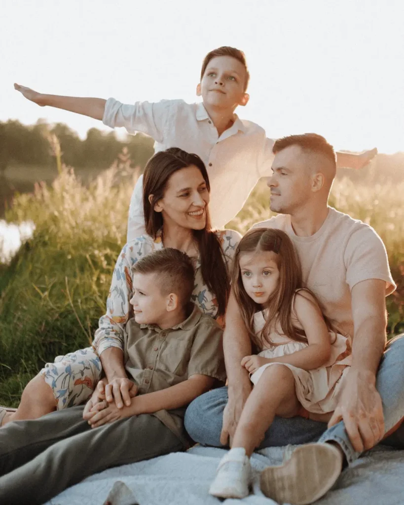 Family Sitting on Meadow at Sunset