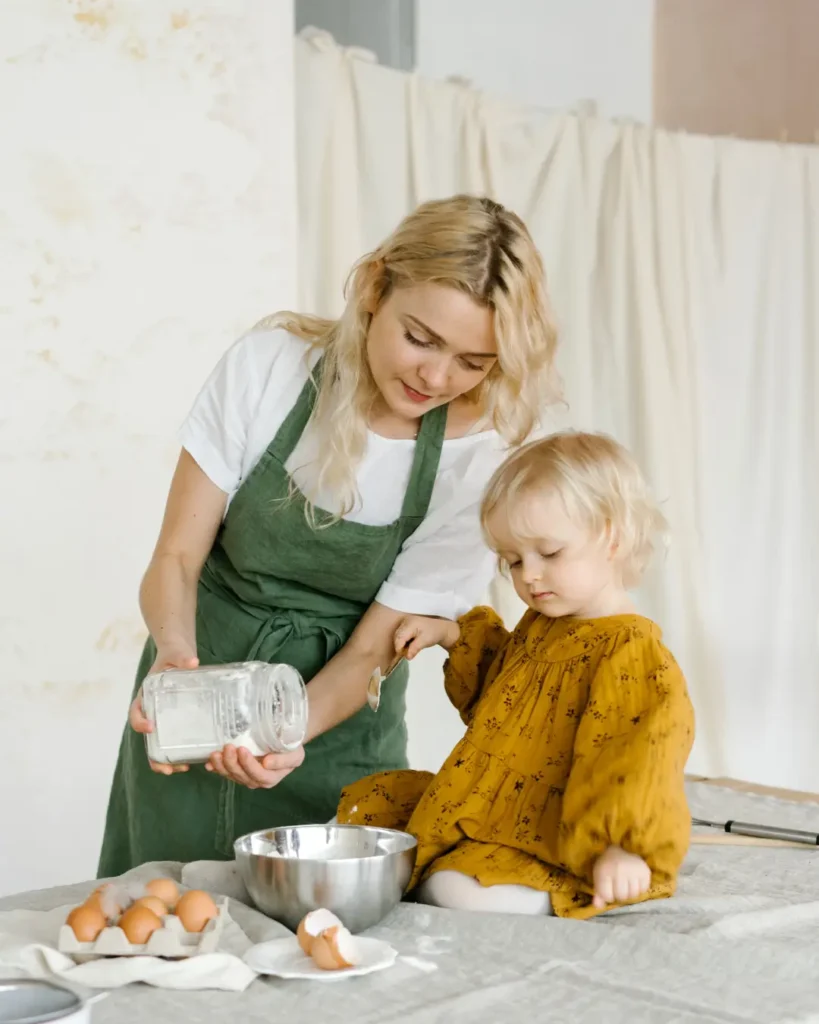Woman cooking near little cute girl on table (1)