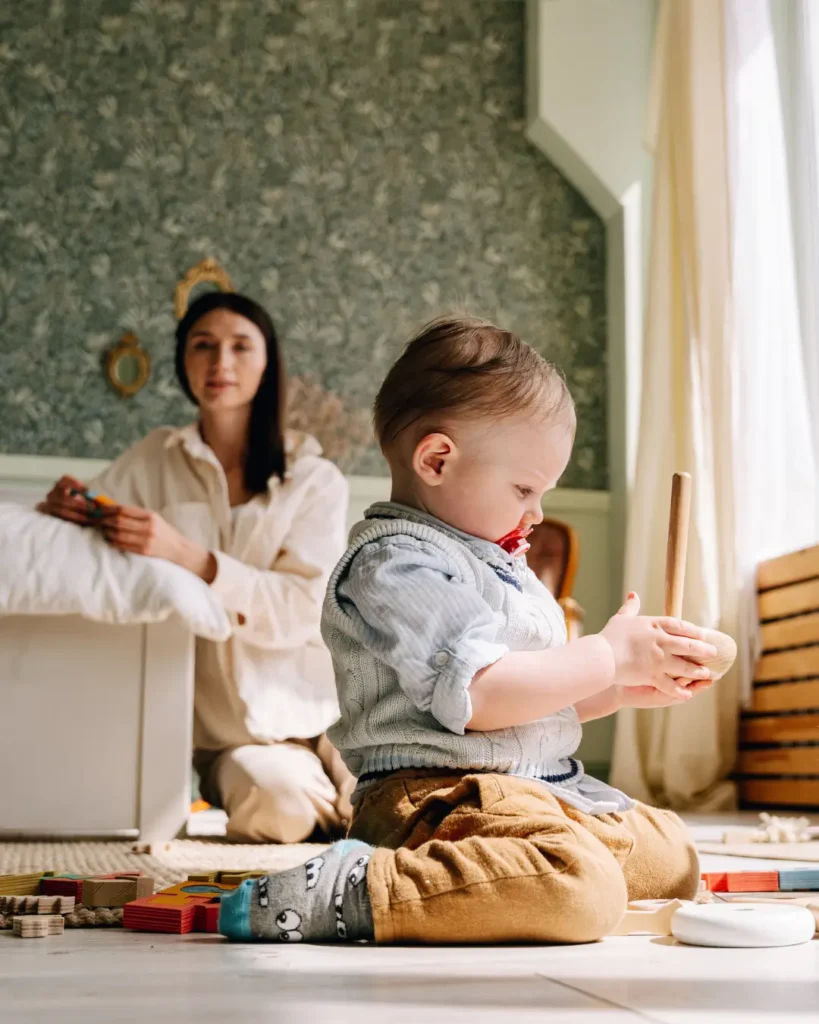 A Woman Looking at the Baby Playing on the Floor 