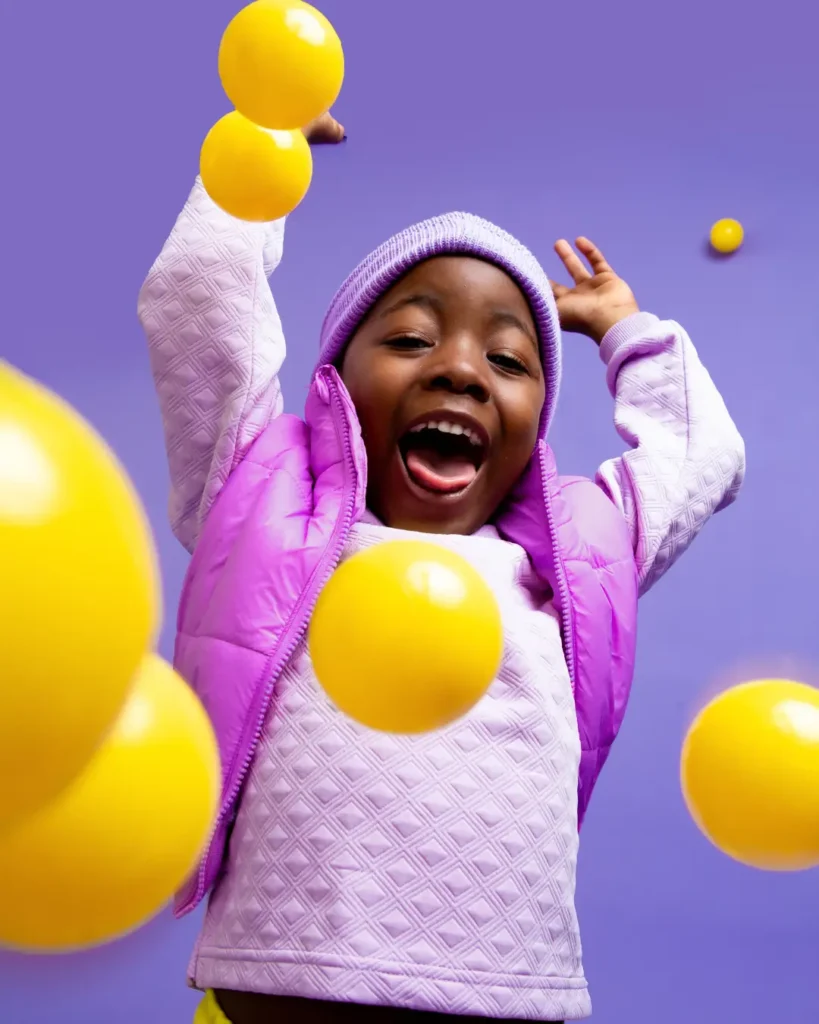 Happy Kid Playing with Yellow Balls
