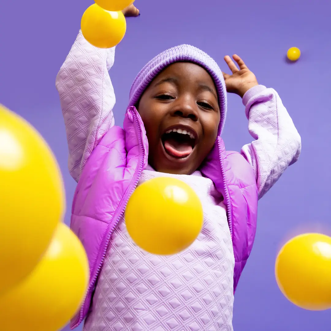 Happy Kid Playing with Yellow Balls