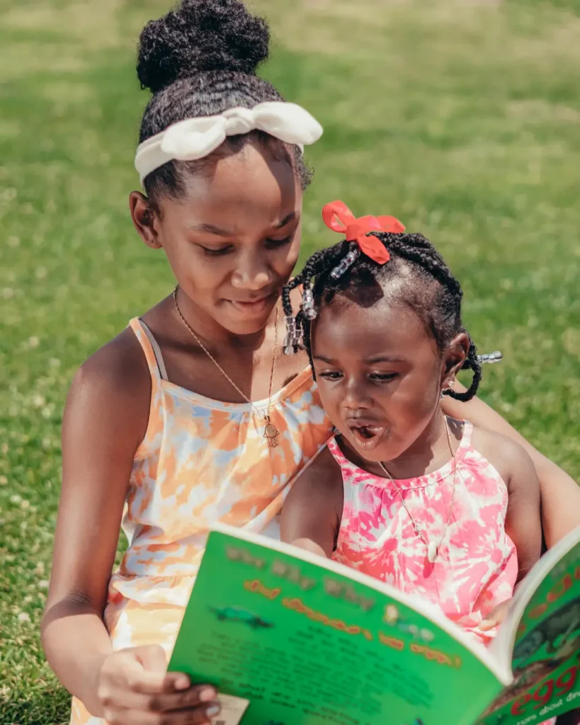 Girls Sitting on Green Grass Field