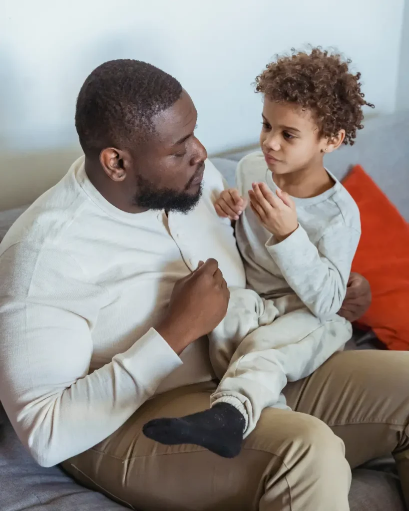 Black man talking with son on knees