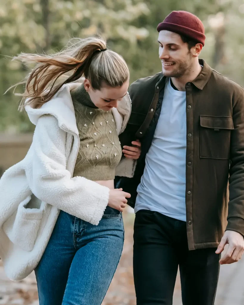 Positive couple walking in park in autumn
