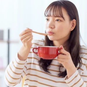 Woman Enjoying a Bowl of Soup in a Cozy Setting